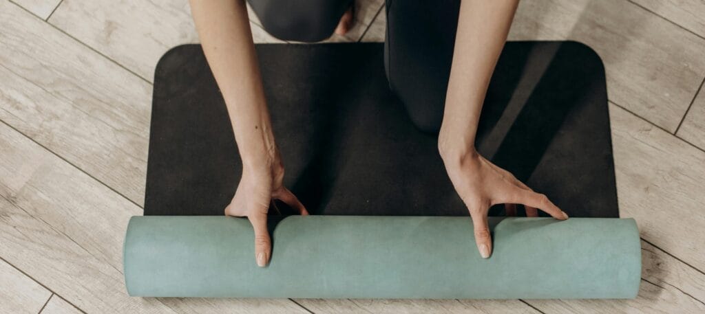 Woman in black leggings unrolling a yoga mat for abdominal muscle separation