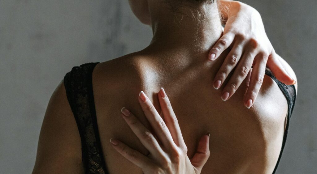 Woman in black tank top with hands on her back